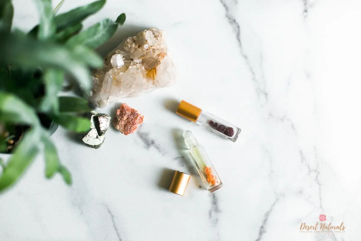 essential oil roller bottles on marble with a plant