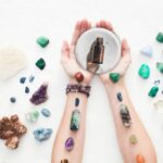 woman's arms with chakra crystals and essential oils