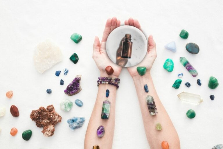 woman's arms with chakra crystals and essential oils