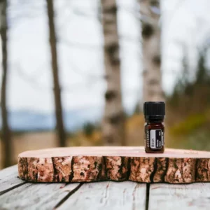 photo of bottle of doterra birch essential oil on wood with trees in background