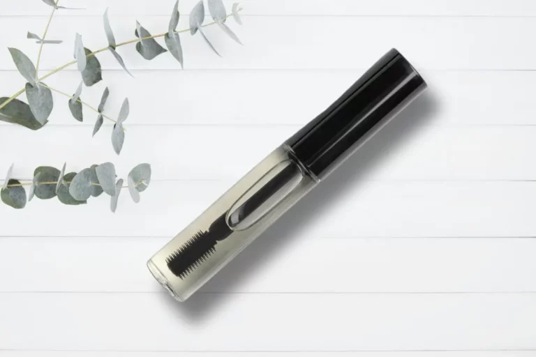 wood background with eucalyptus and tube of diy eyelash serum