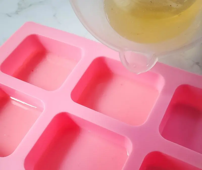 image of pouring melted soap base into rectangle soap molds