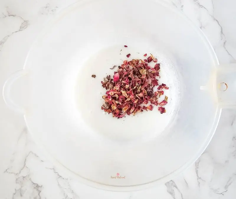 image of adding dried rose petals to the melt and pour soap base for diy rose sugar scrub bars