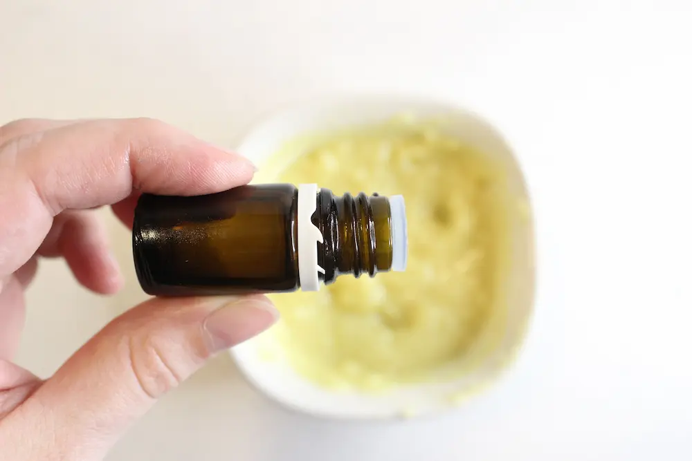 adding essential oils to diy oatmeal body butter in a bowl