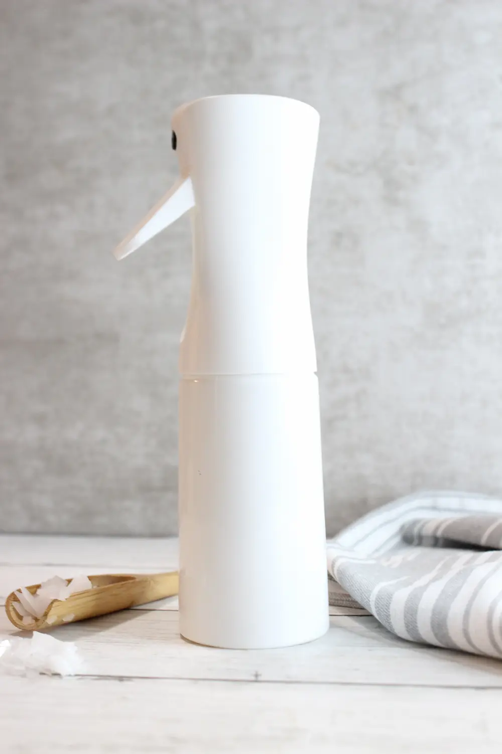a bottle of magnesium spray with a wooden spoon containing magnesium flakes