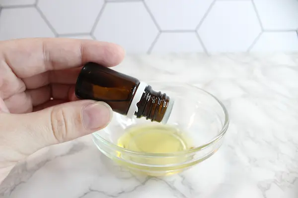 adding essential oil to a bowl of carrier oil for magnesium spray