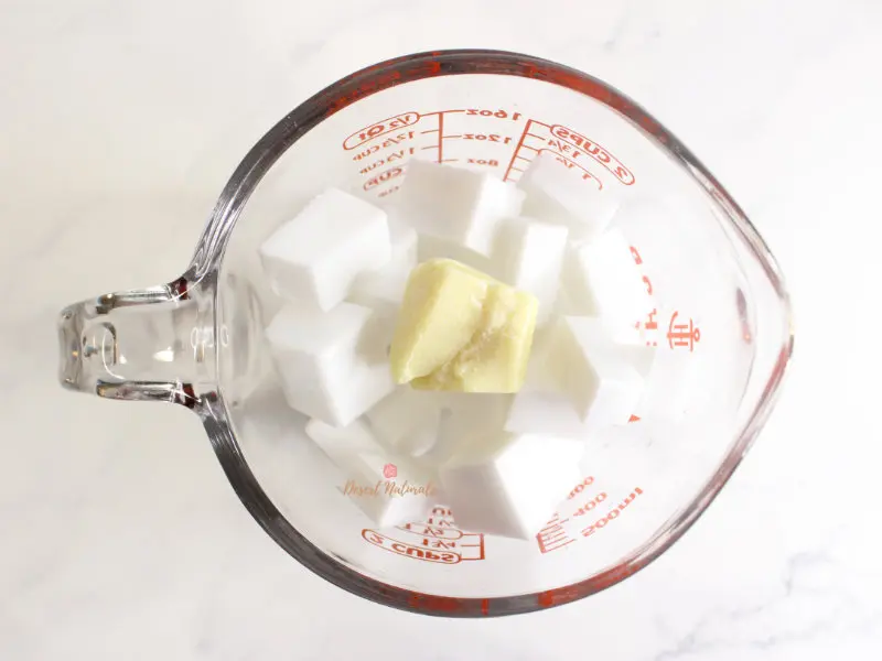 photo of cut up melt and pour soap base and cocoa butter in a glass measuring cup to melt for making homemade shampoo bars