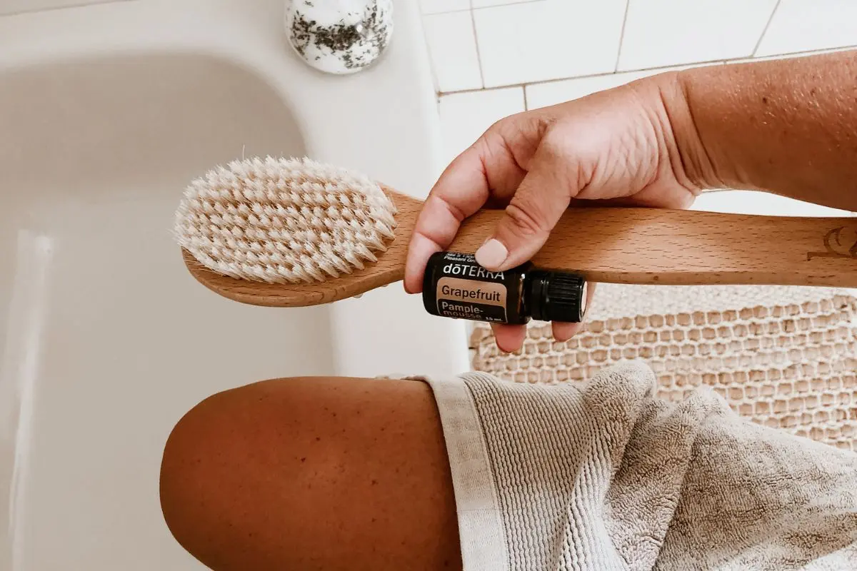 woman in bathtub with dry brush and grapefruit essential oil