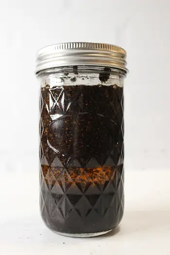 glass mason jar of coffee infused oil to use in coffee oatmeal body scrub