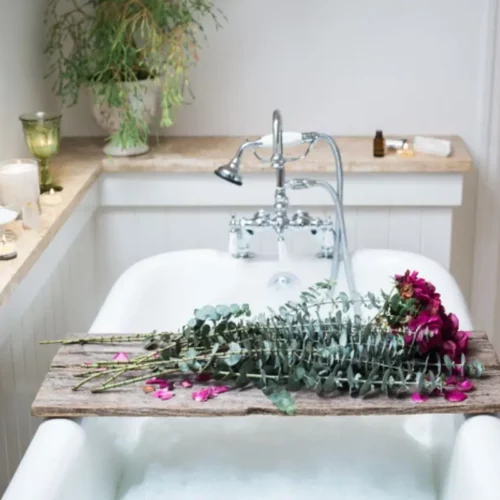 beautiful photo of self care bath with roses, essential oils, and candles
