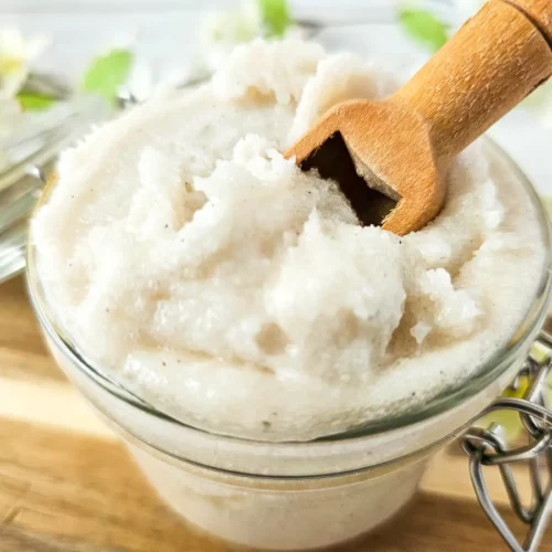 photo of glass jar filled with homemade lemon vanilla whipped sugar scrub with a wooden spoon