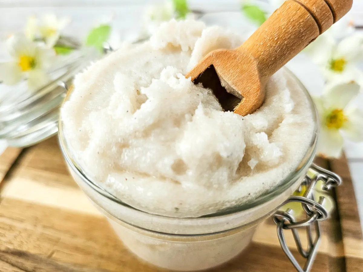 photo of glass jar filled with homemade lemon vanilla whipped sugar scrub with a wooden spoon