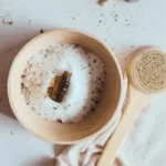photo of epsom salts in a bowl with a bottle of essential oil and a dry brush