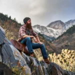 a rugged mountain man sitting on a rock