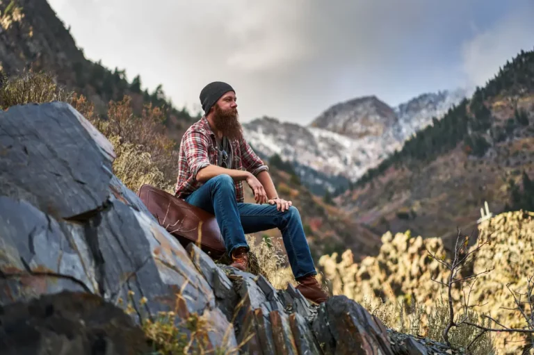 a rugged mountain man sitting on a rock