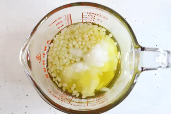 a measuring cup with shea butter, beeswax and coconut oil to melt down for making diy sunscreen