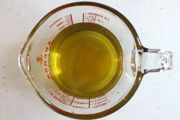 a glass measuring cup with melted butters and oils for making homemade sunscreen