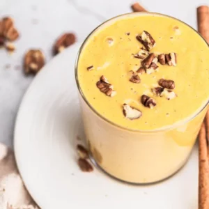 a glass of pumpkin smoothie with nuts on top