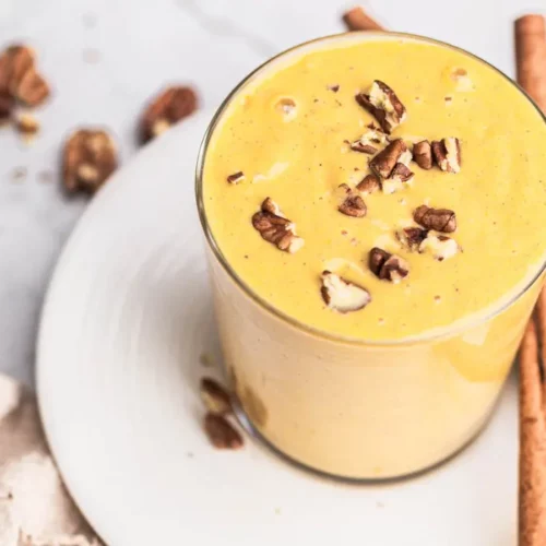 a glass of pumpkin smoothie with nuts on top