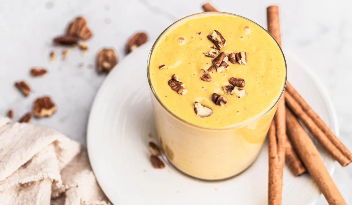 a glass of pumpkin smoothie with nuts on top