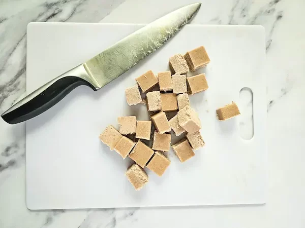 a cutting board and knife with pumpkin pie sugar scrub cubes on it