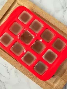 a silicone mold with 12 squares and melted butters in it for making lotion bars