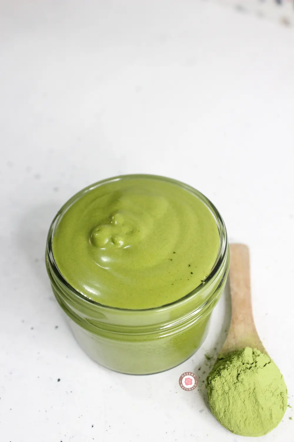 jar of homemade green tea matcha face cream with a wooden spoon for application