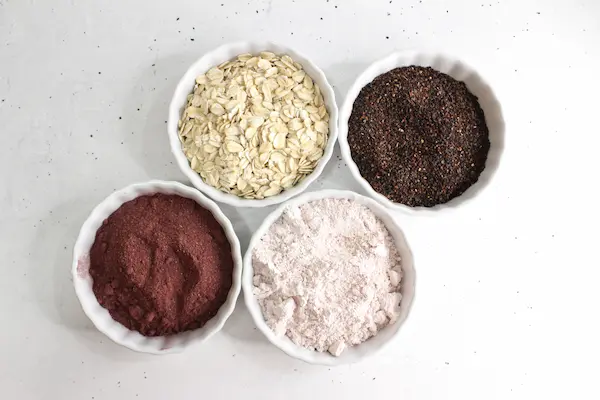 bowls of hibiscus powder, rose hip powder, and oats for making a homemade scrub.