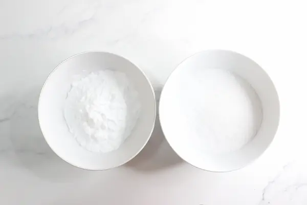 two bowls one with epsom salts and one with baking soda for making bath salts