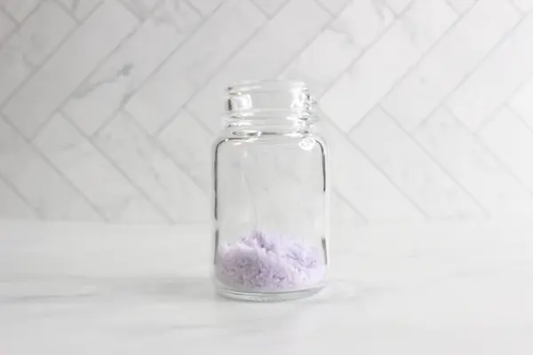 a clear glass jar with purple bath salts in it