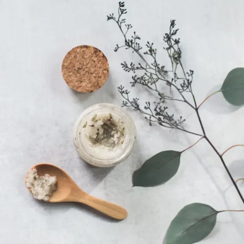 homemade scrub in a pot with a wooden spoon and eucalyptus greenery
