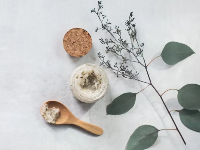 homemade scrub in a pot with a wooden spoon and eucalyptus greenery