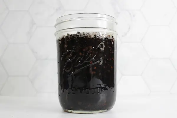 a glass mason jar with elderberries and water making a tea