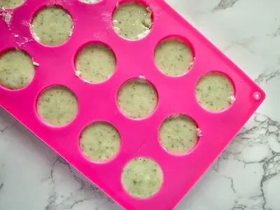 a pink silicone soap mold with a green tea sugar scrub mixture poured into it.