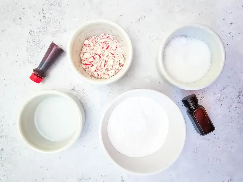 bowls of ingredients and essential oil needed to make candy cane shower bombs