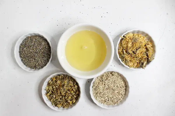 bowls of herbs and oil to make an herbal infusion for a diaper rash cream