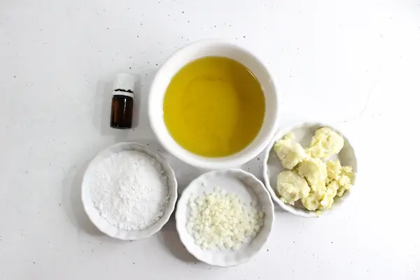 bowls of ingredients and essential oil needed to make homemade diaper rash cream