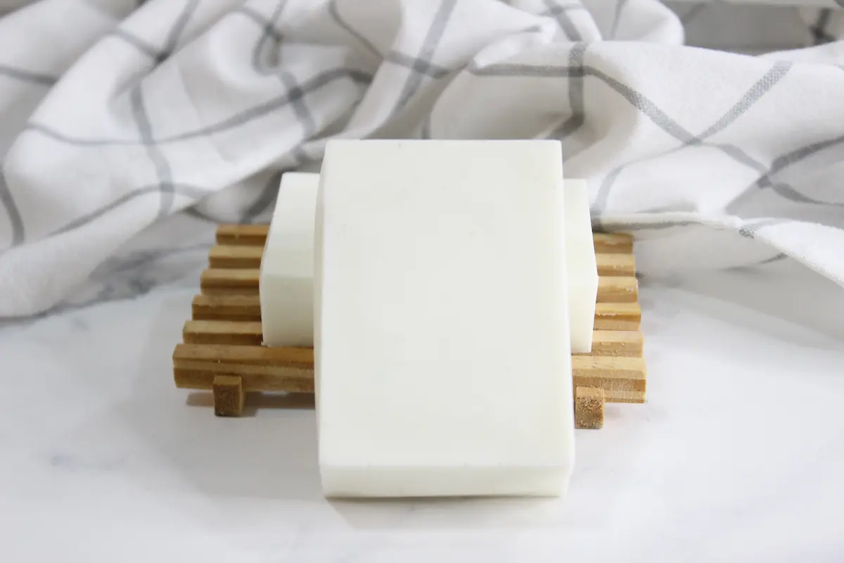 Easy Tallow Soap DIY Recipe to Moisturize Dry Skin 11 bars of homemade diy tallow soap on wooden soap holder with a towel in the background