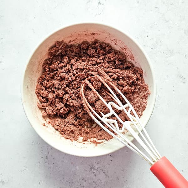 bowl of mixed ingredients with a whisk for making gingerbread shower bombs