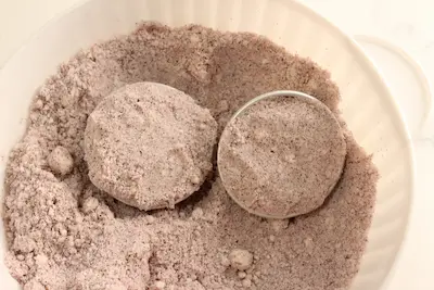 2 filled bath bomb molds in a bowl of hibiscus bath bomb mixture