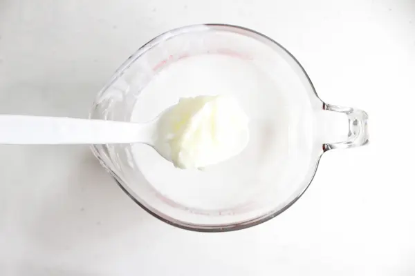 tallow sitting in melted melt and pour soap base inside a glass measuring cup
