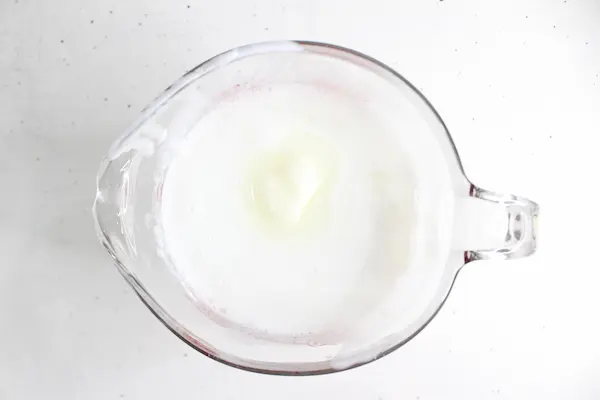 tallow sitting in melted melt and pour soap base inside a glass measuring cup