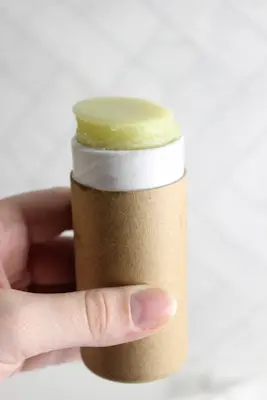hand holding a cardboard tube of diy tallow balm