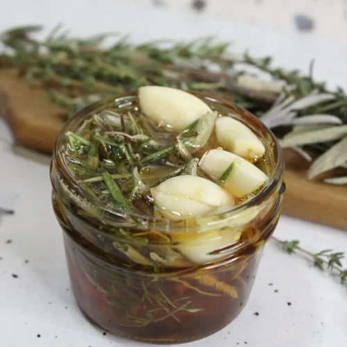 jar of homemade herb infused honey with garlic and dried herbs
