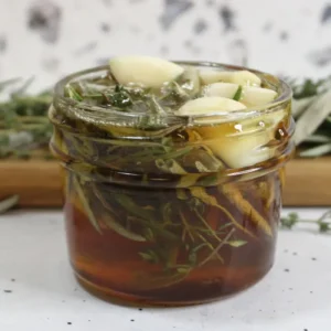 jar of homemade herb infused honey with herbs on a cutting board