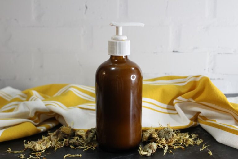 brown glass pump bottle of homemade honey calendula face wash with dried flowers