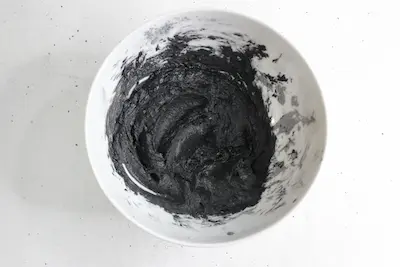 a bowl of mixed ingredients including activated charcoal for making natural toothpaste