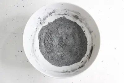 a bowl of dry ingredients including activated charcoal for making natural toothpaste