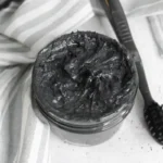 jar of homemade natural charcoal toothpaste with a toothbrush