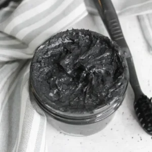jar of homemade natural charcoal toothpaste with a toothbrush